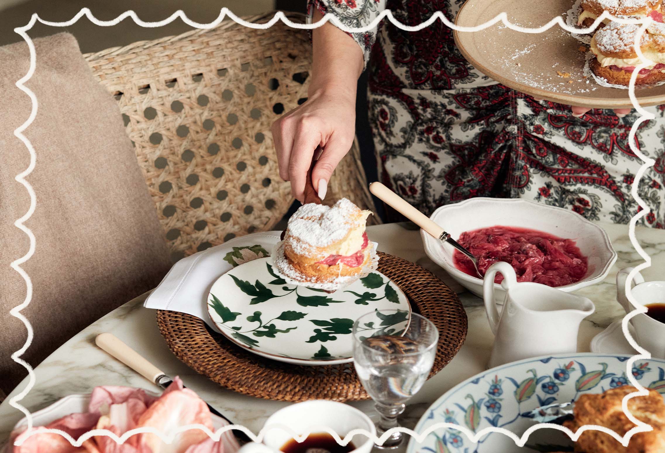 Claire serves a scone on a white china plate decorated with a green leaf pattern