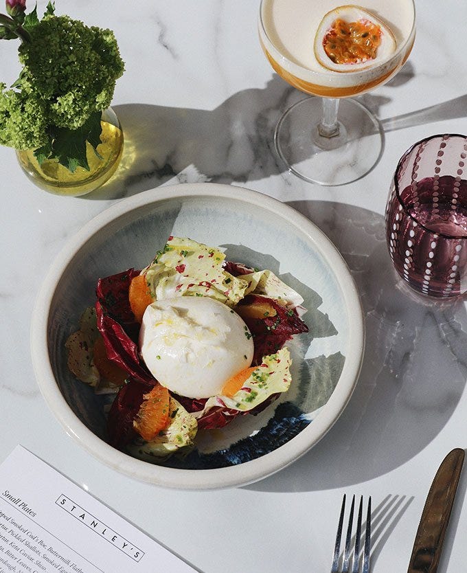 Bowl of salad and burrata on a marble table
