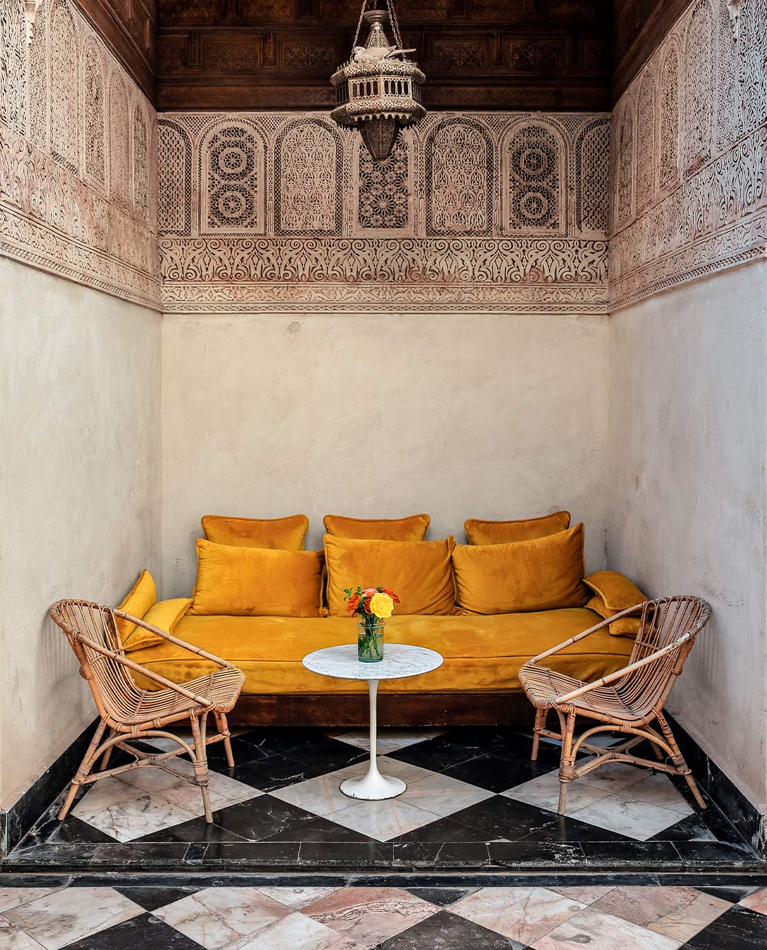 A velvet, mustard yellow sofa in a black-and-white tiled room