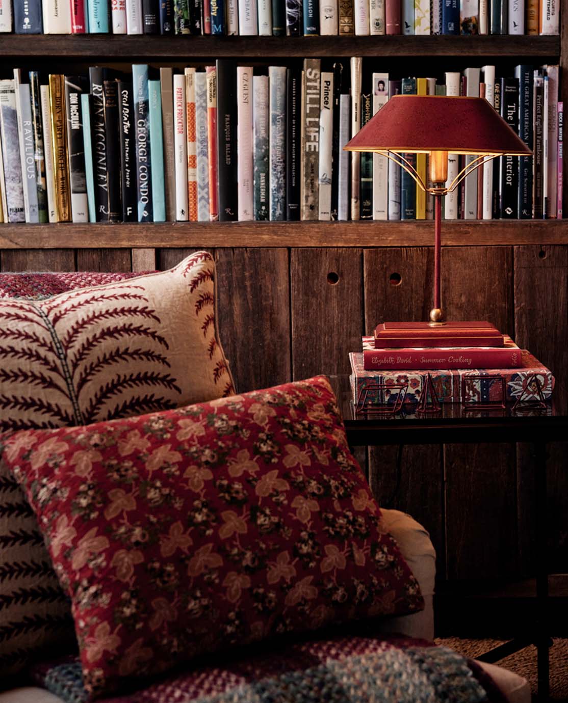 A cozy corner with an armchair, red pillows and a bookcase