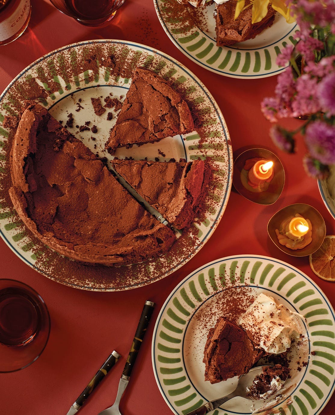 Green striped tableware serving a chocolate dessert on a dining table lit with candles.