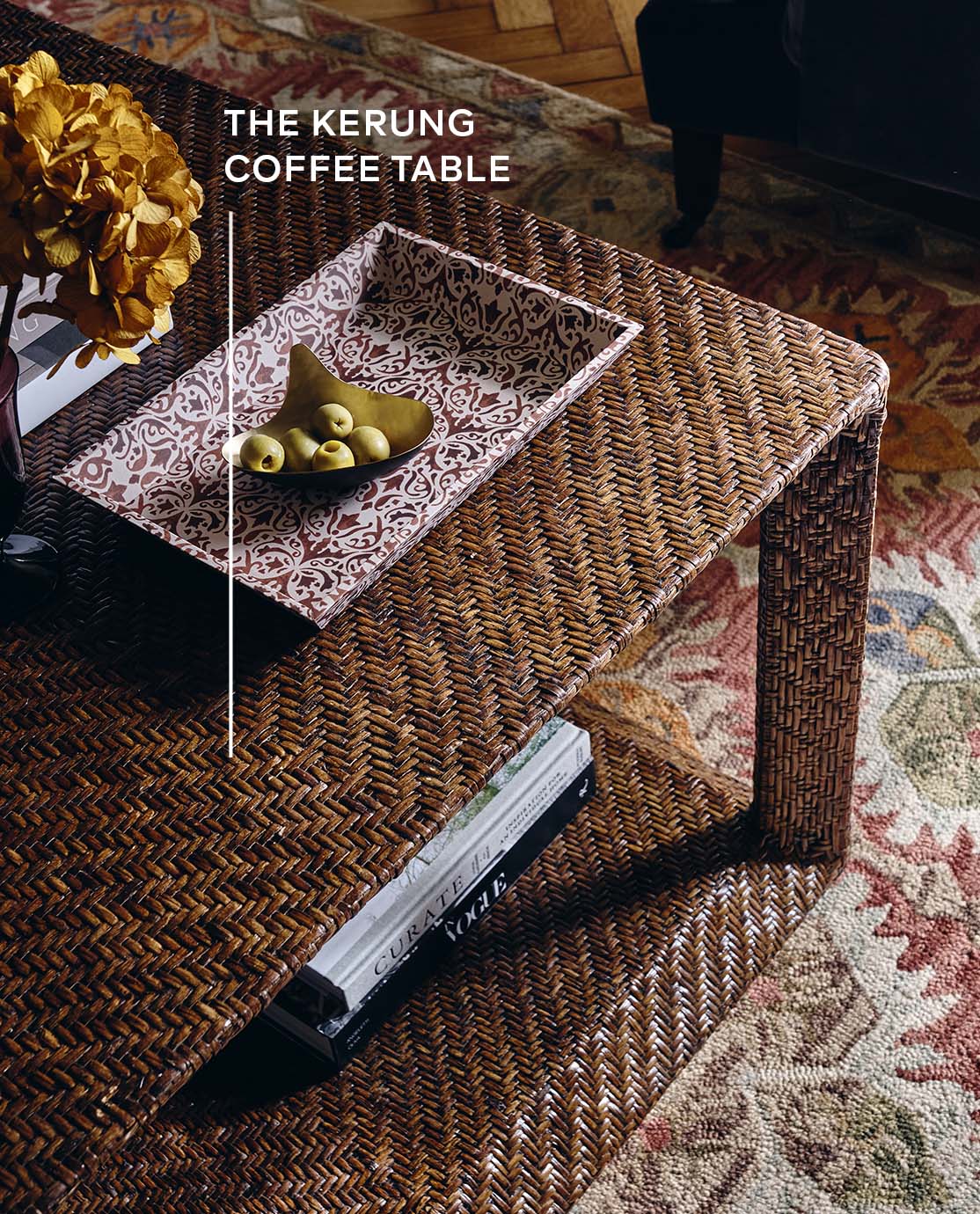 A woven rattan coffee table with a red patterned tray and yellow flowers.