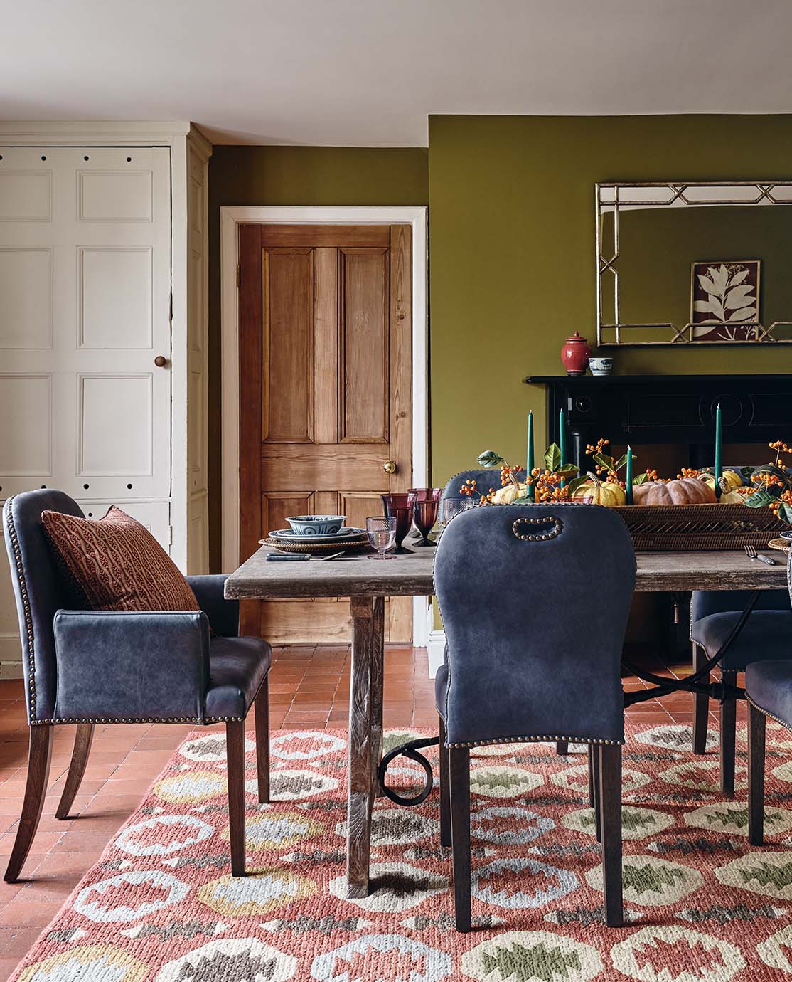 A dining room with blue leather dining chairs and a wooden dining table on a patterned rug.