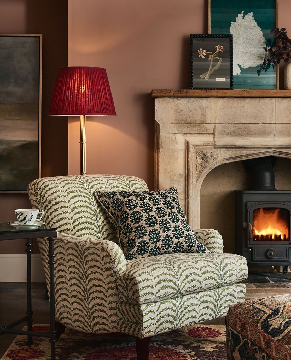 A palm-print armchair, decorated with a blue patterned cushion, sits in front of a fireplace.