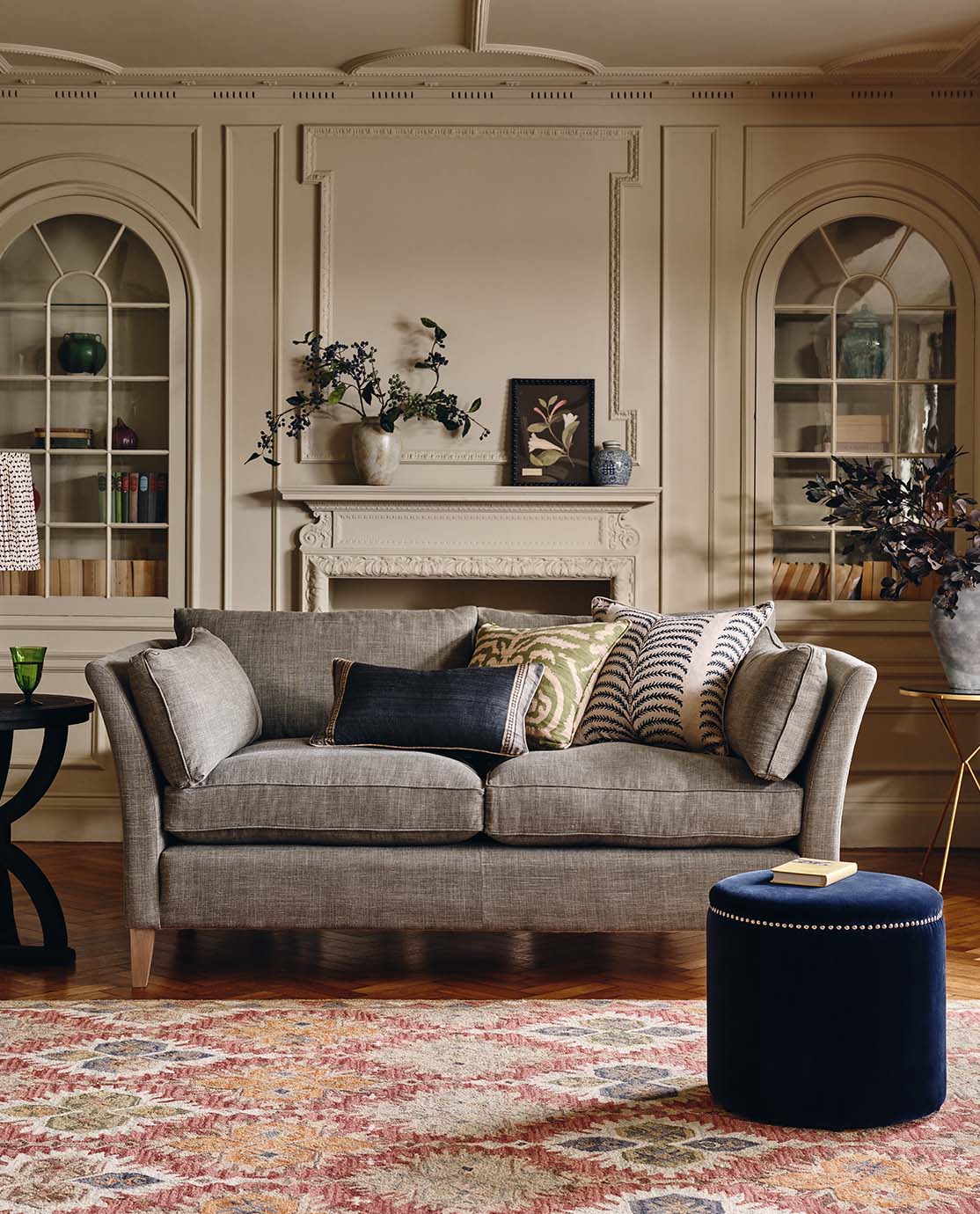 A green velvet sofa, decorated with printed pillows.