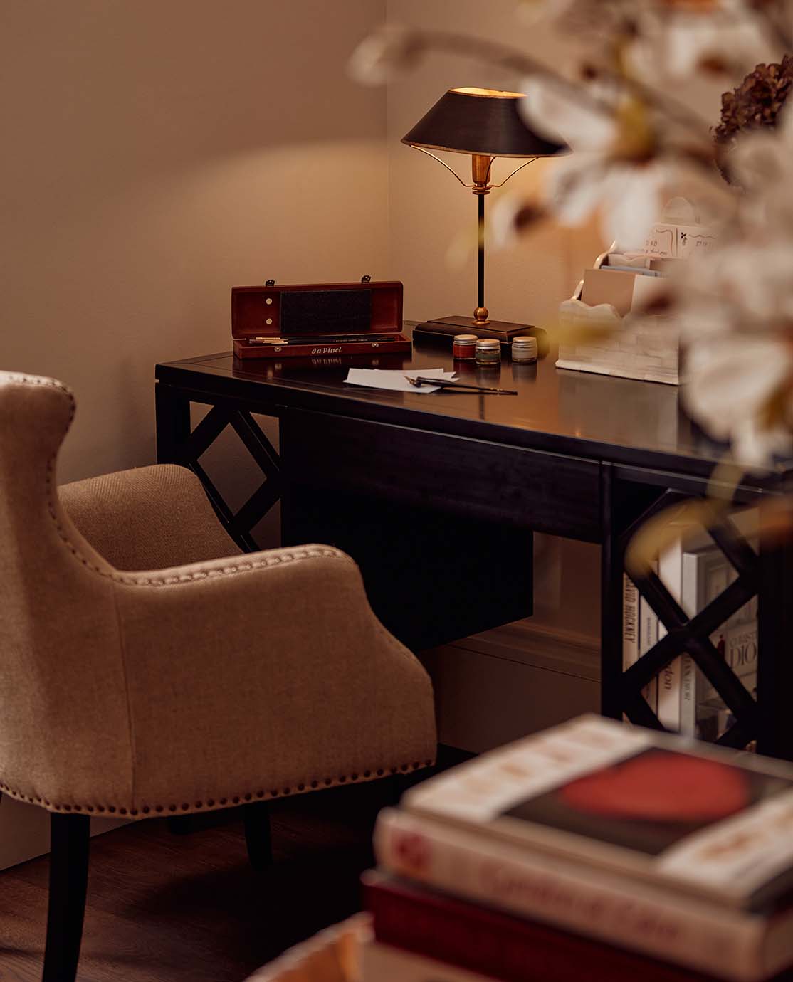 A home study setting with a black desk, neutral-colored armchair and desk accessories