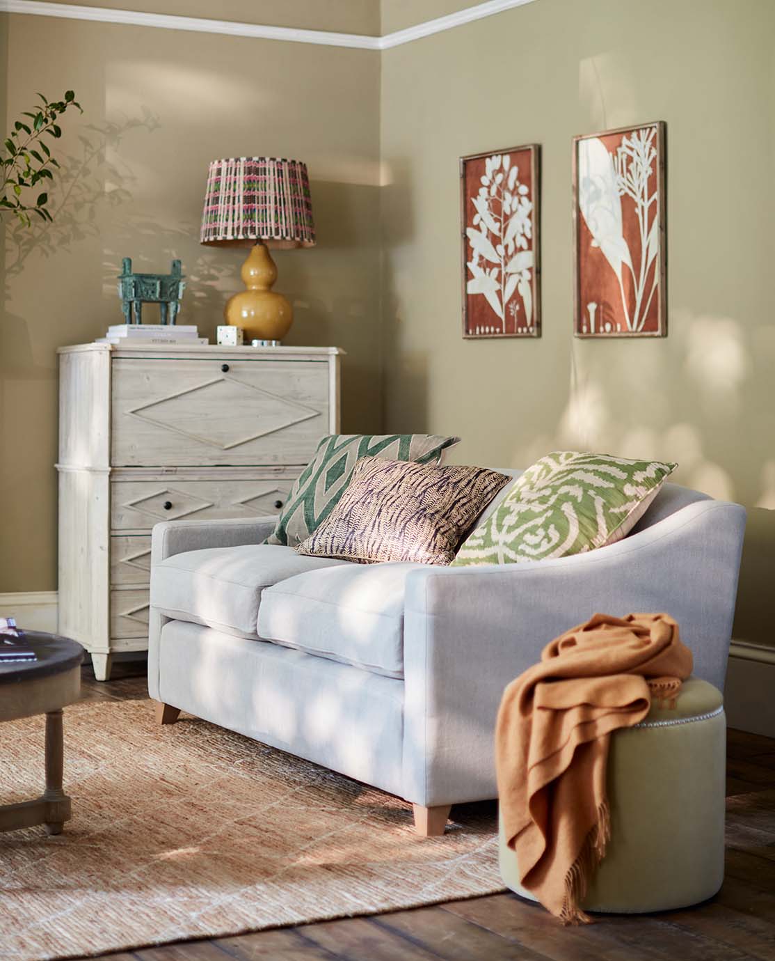 An orange-brown two-seater linen sofa standing in front of large Crittall-style doors