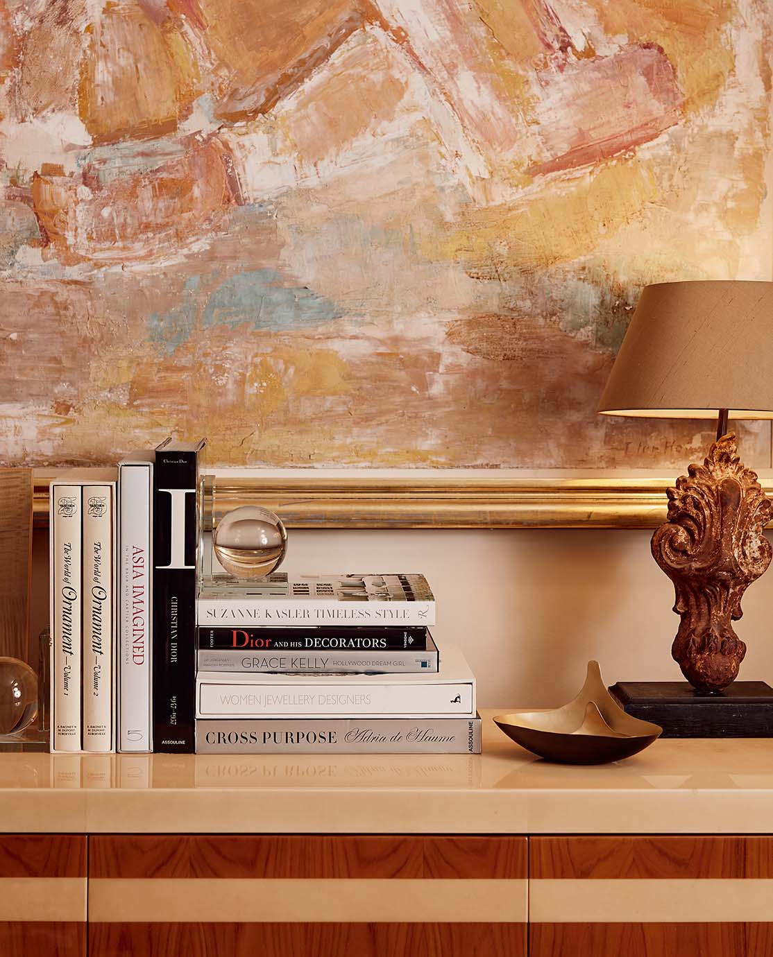 A console table decorated with coffee table books, ornaments and a lamp