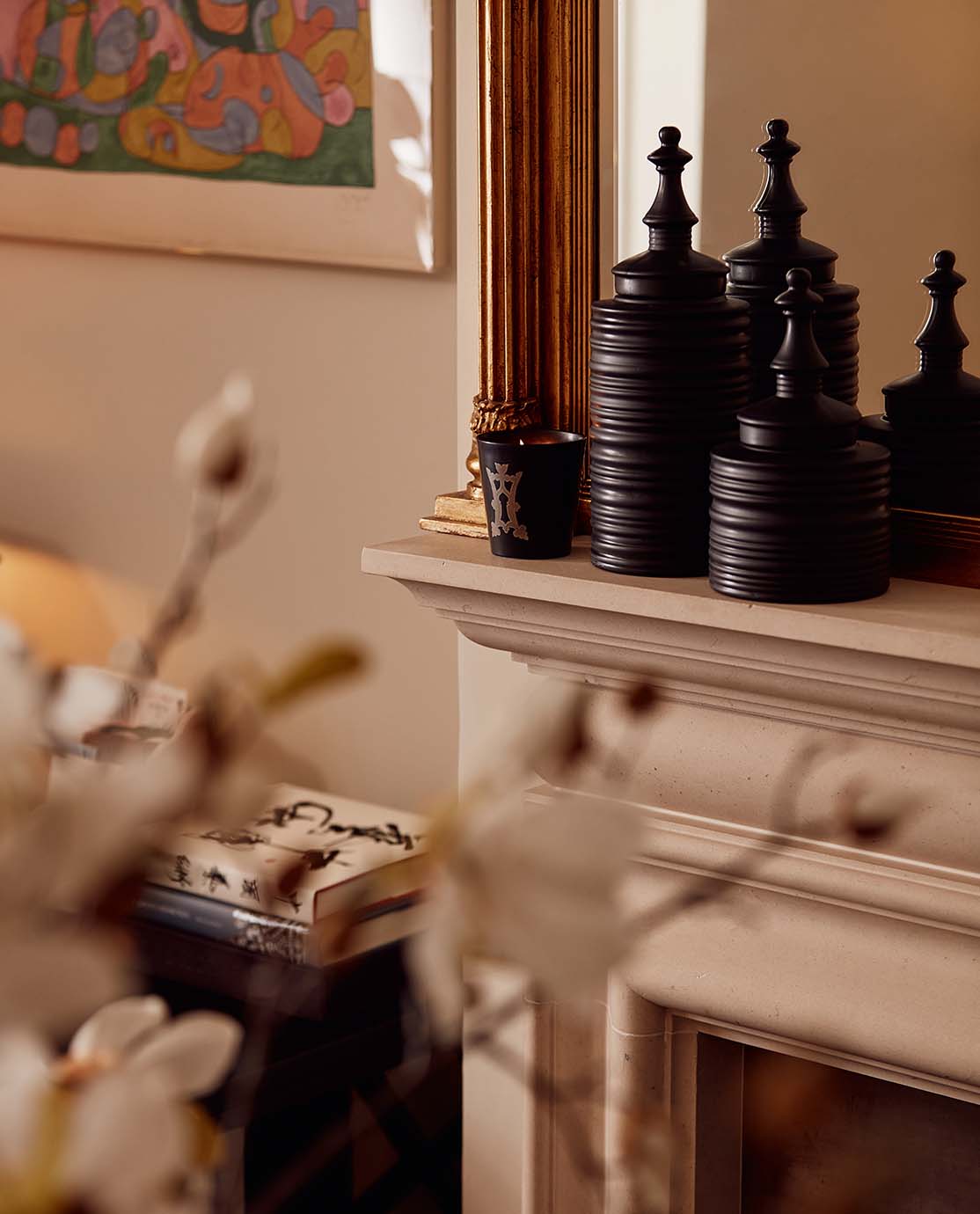 The corner of a white marble mantelpiece decorated with a candle and two black pots