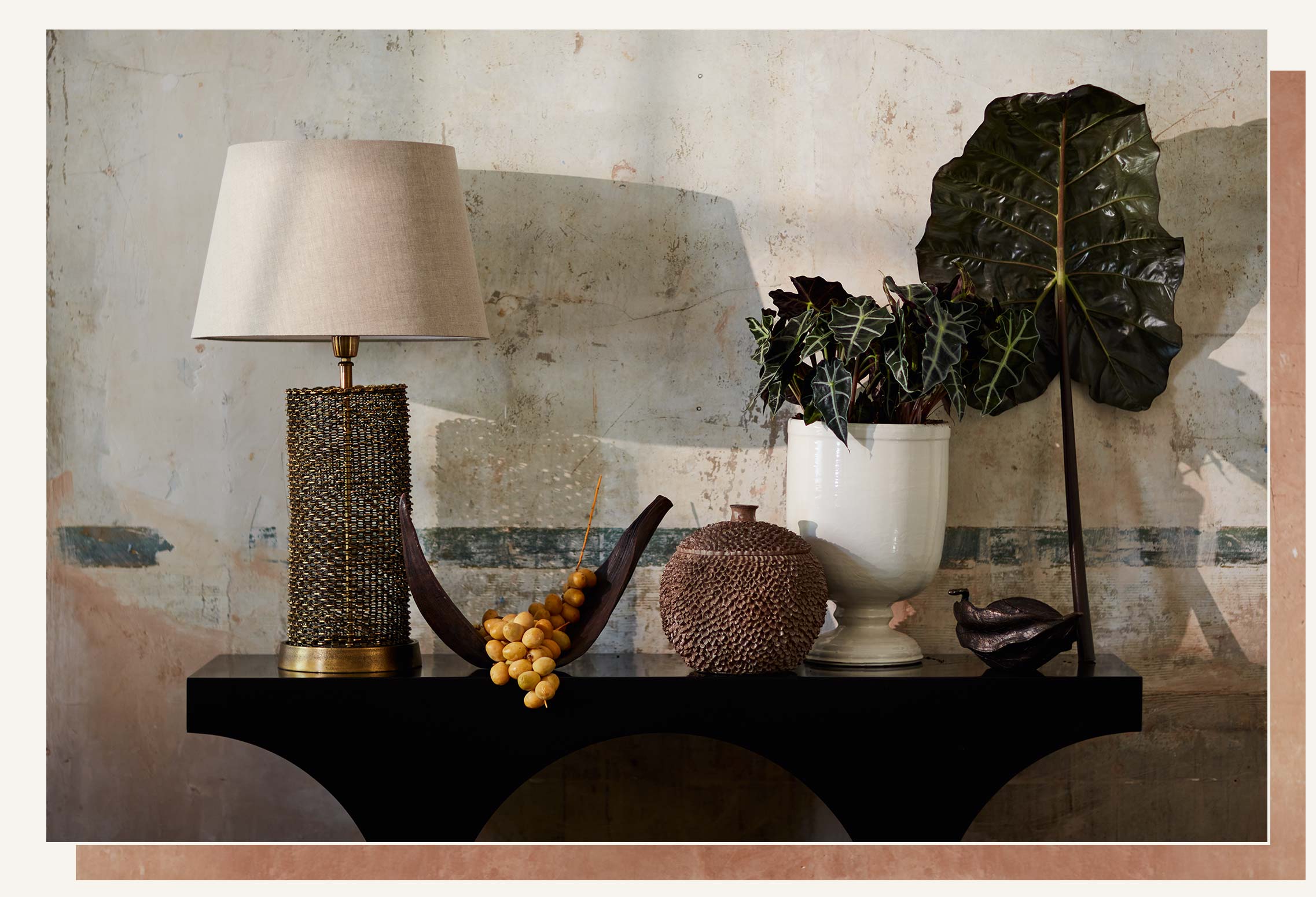 A black console table is decorated with a gold lamp and nature-inspired ornaments