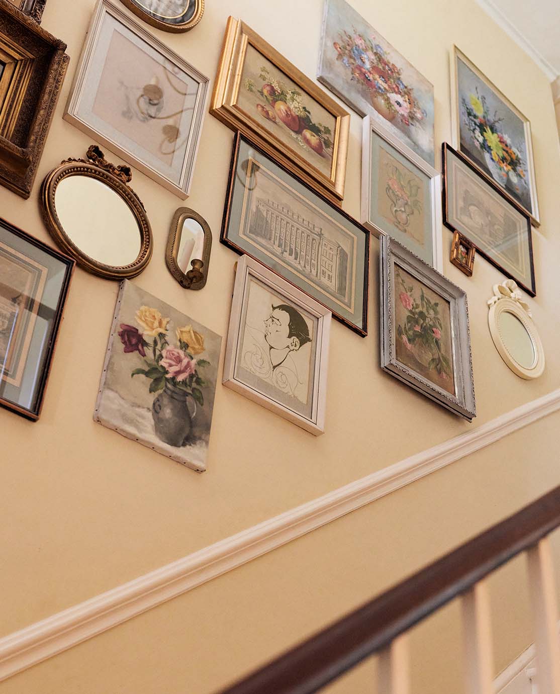 A staircase wall decorated with lots of antique frames and prints