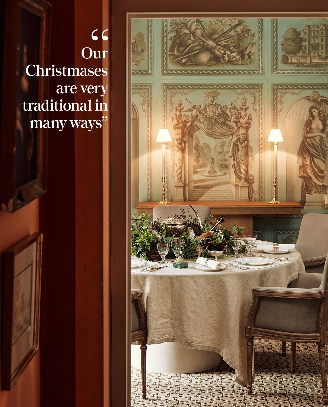 A grand dining room featuring a dining table decorated for Christmas with foliage, glassware, white crockery and napkins