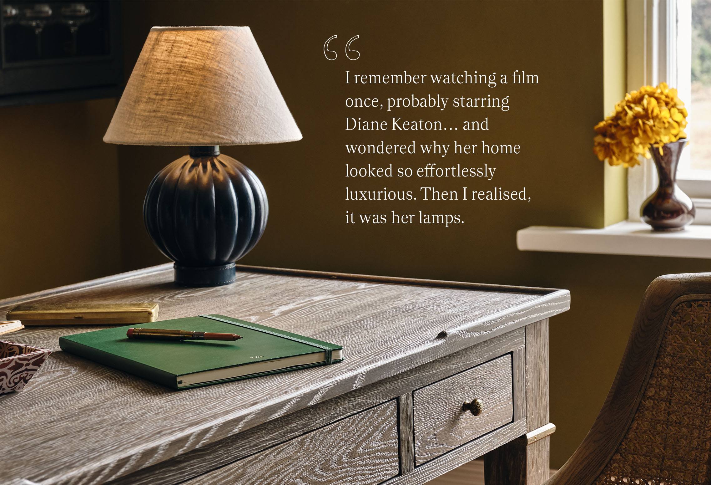 A wooden desk featuring a a blue lamp with a cream lamp shade, accompanied by a quote from Jack Guinness. 