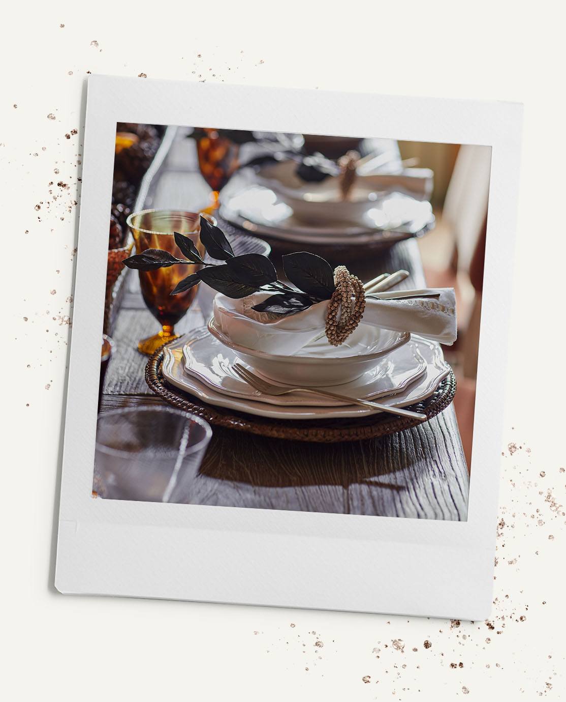 A festive table setting, featuring a rattan charger, white dinner plates and a napkin decorated with a faux leaf