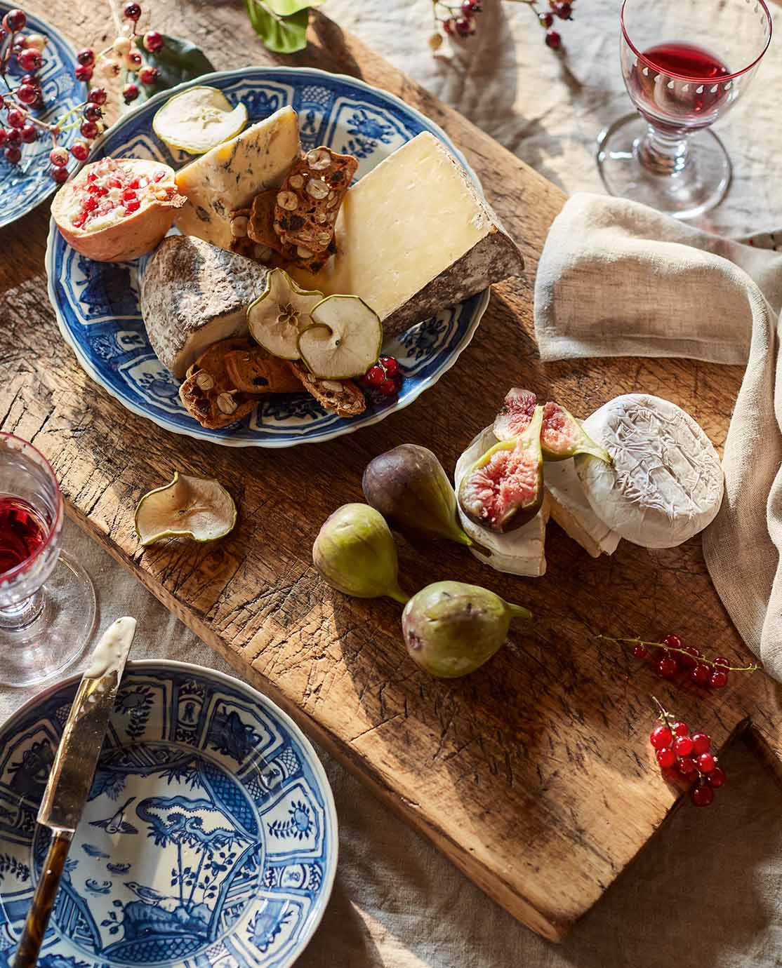 A wooden board serving a selection of cheese and fruit