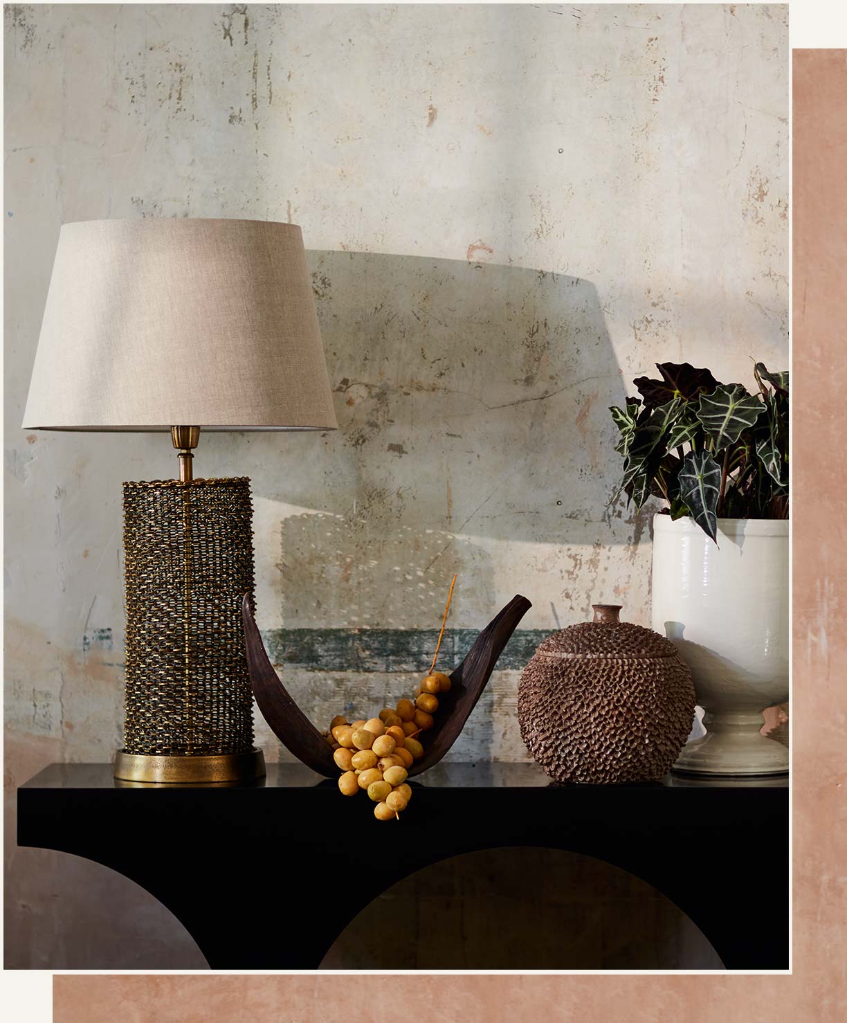 A black console table is decorated with a gold lamp and nature-inspired ornaments