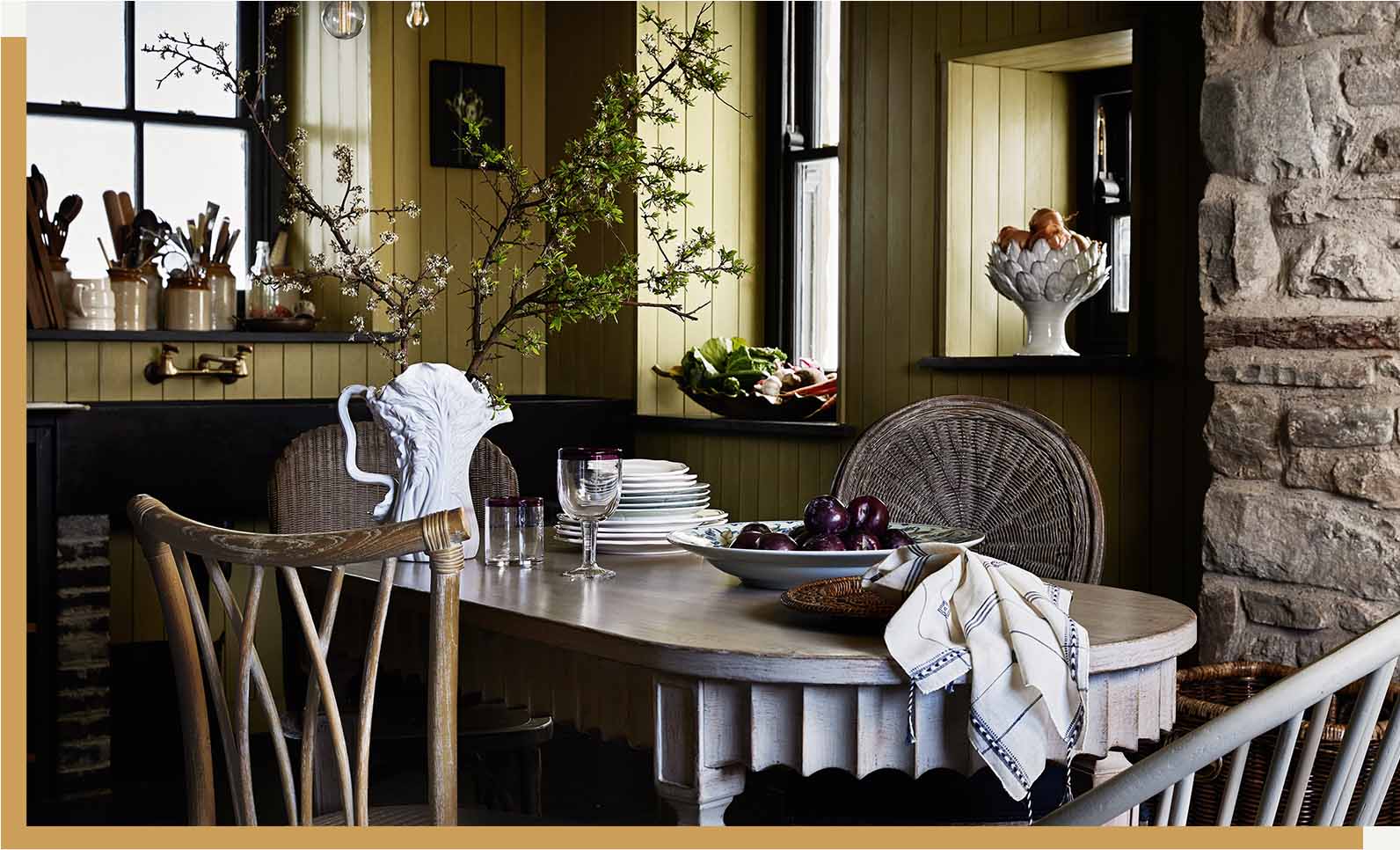 A yellow dining room with a large dining table and mixed chairas