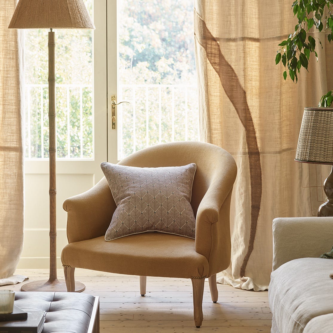 Yellow armchair with natural colour cushion in front of open large french doors