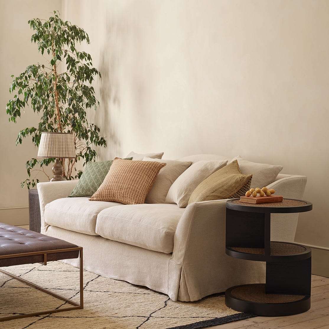 Natural colour linen sofa with an array of pastel coloured cushions scattered.