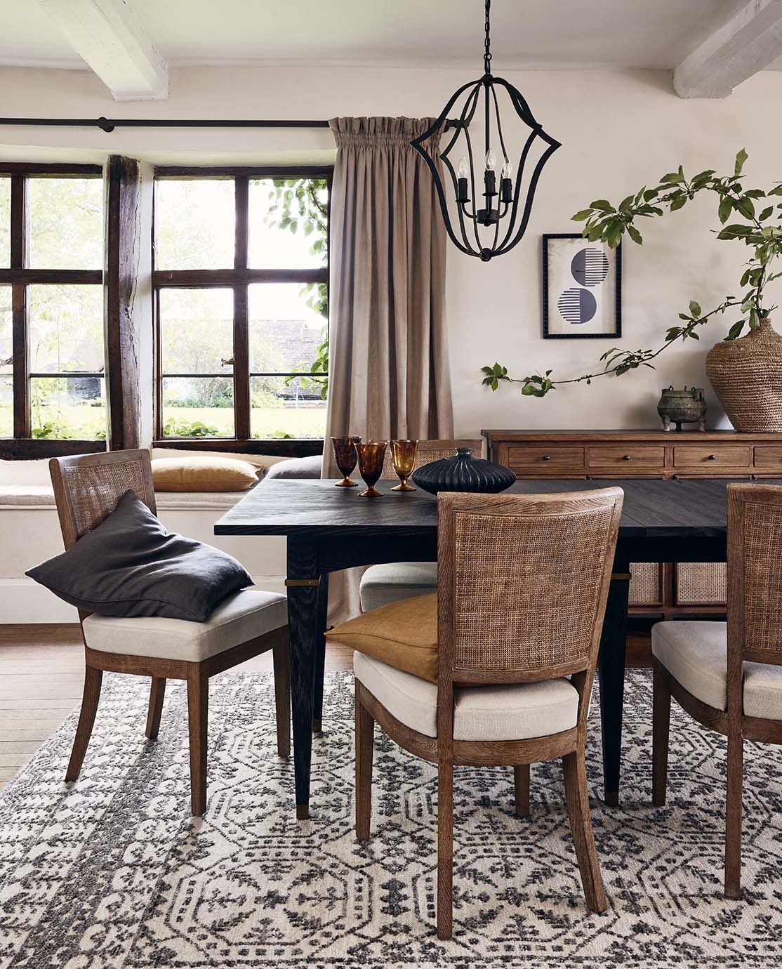 A countryside dining room setting, with rattan chairs and black accents