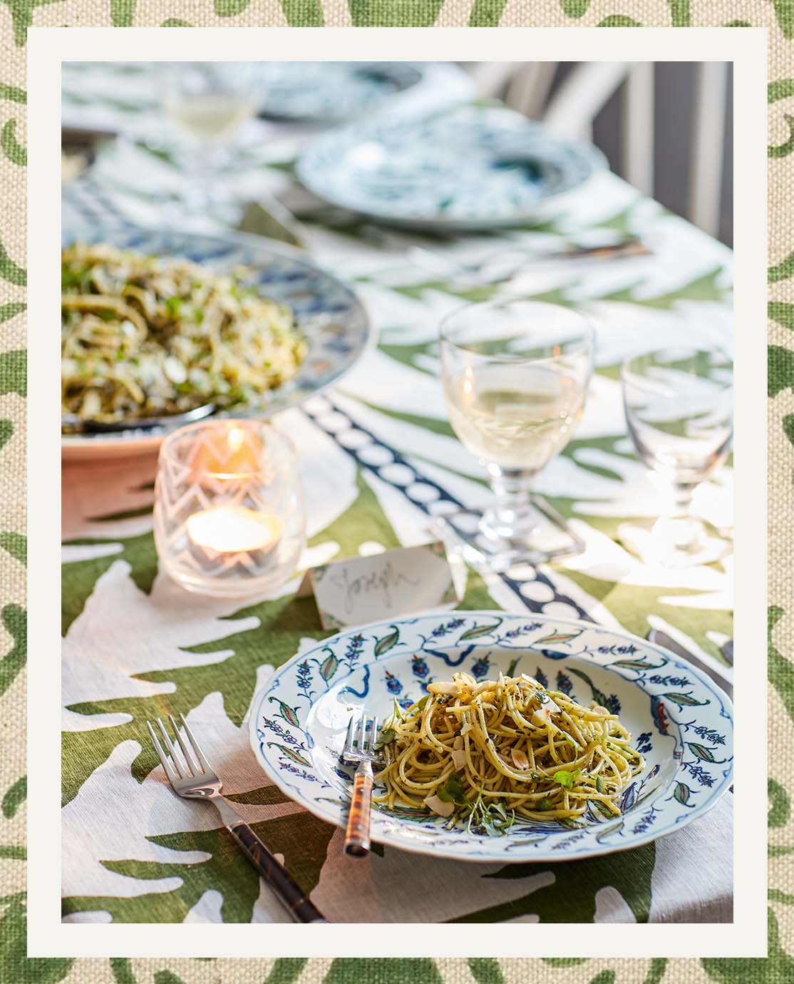 A green and blue tablescape with a leaf-print tablecloth and floral crockery.