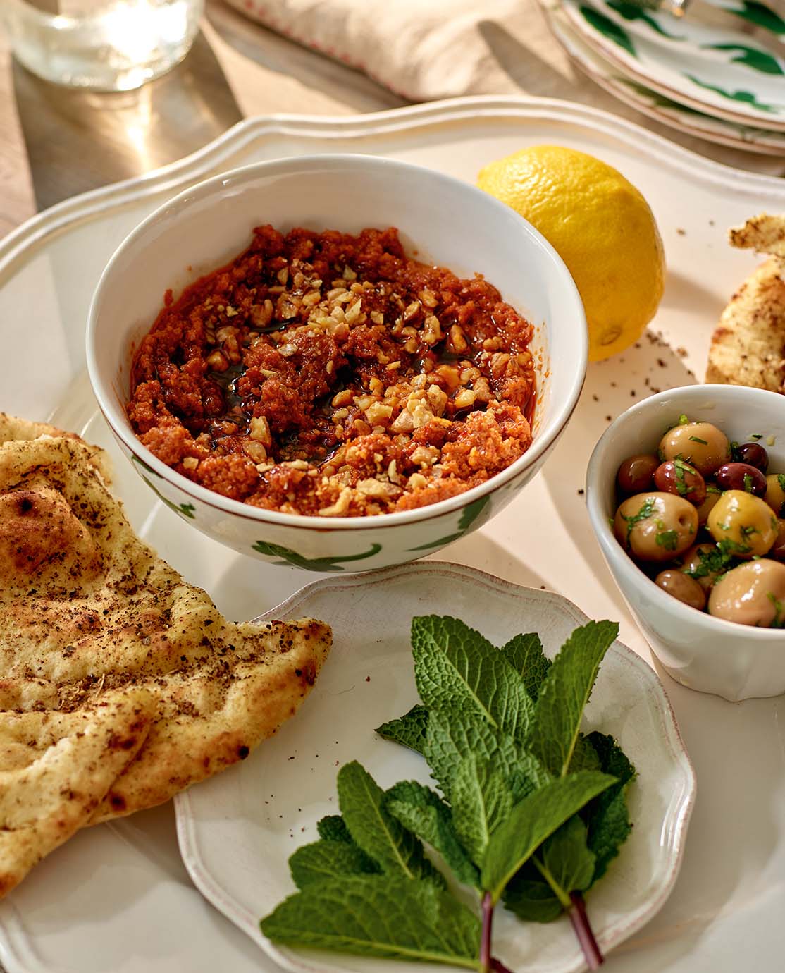A traditional Turkish dip presented in a patterned bowl, next to a bowl of olives and some flatbread.