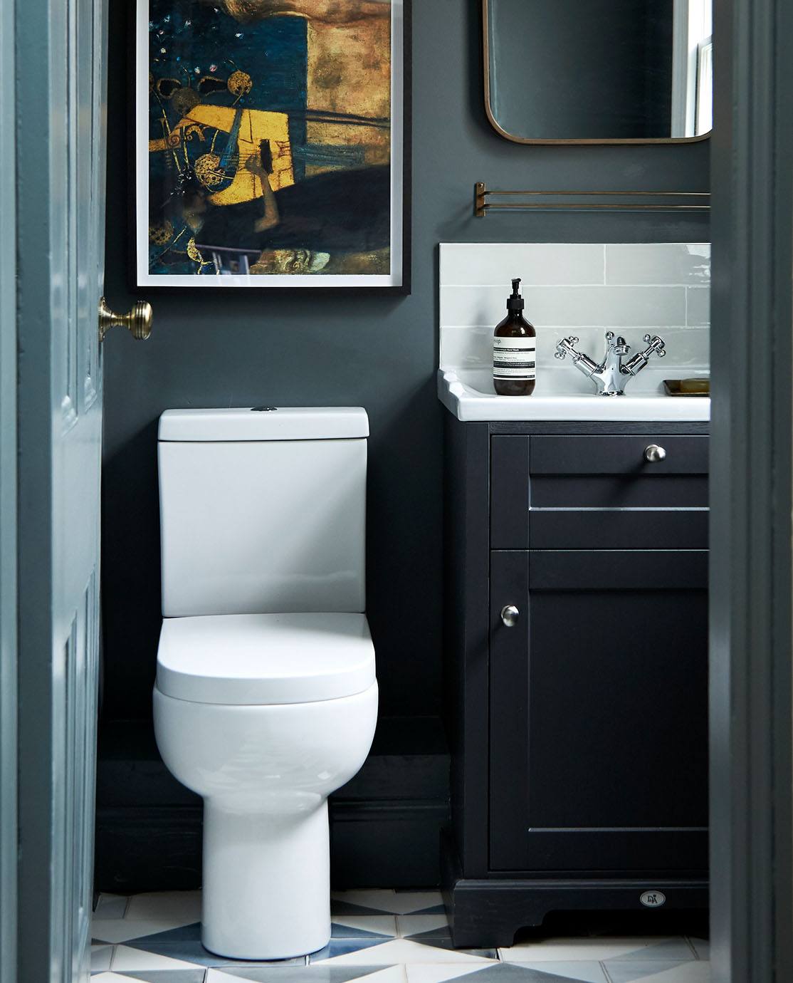 Looking through a bathroom door; the space is painted in dark colours of navy and petrol