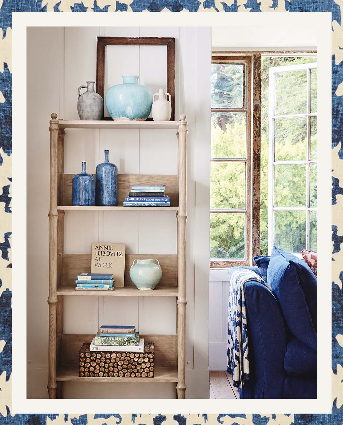 A wooden bookcase is decorated with blue, white and wooden accessories