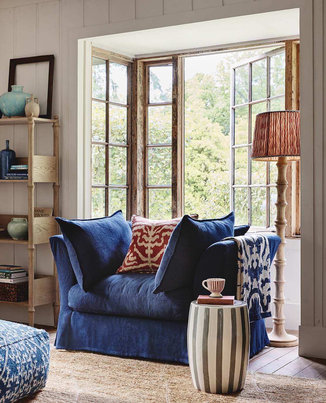 A large navy blue linen armchair is decorated with patterned red cushion