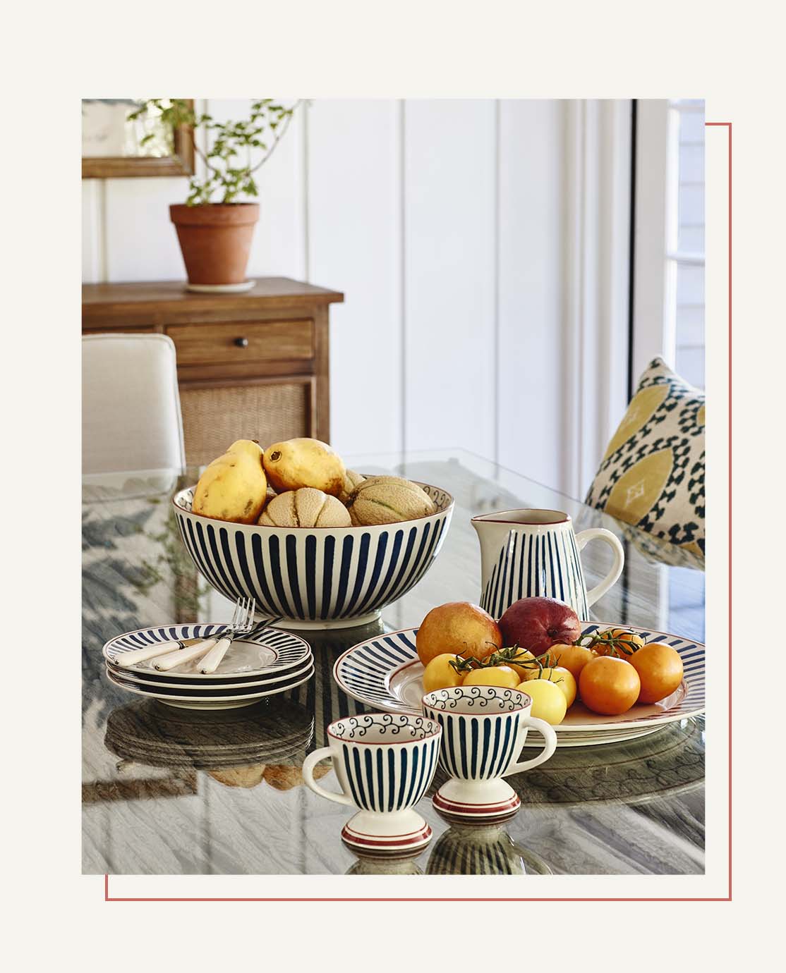 A close-up of a glass-covered tabletop, decorated with blue, white and red striped crockery.