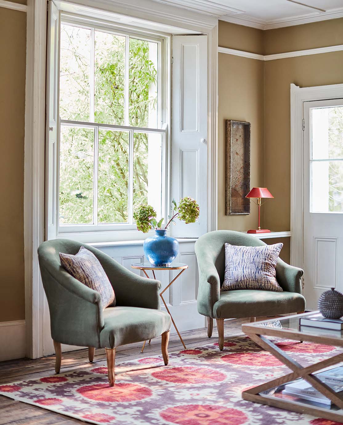 Two green armchairs sit on a red and purple patterned rug