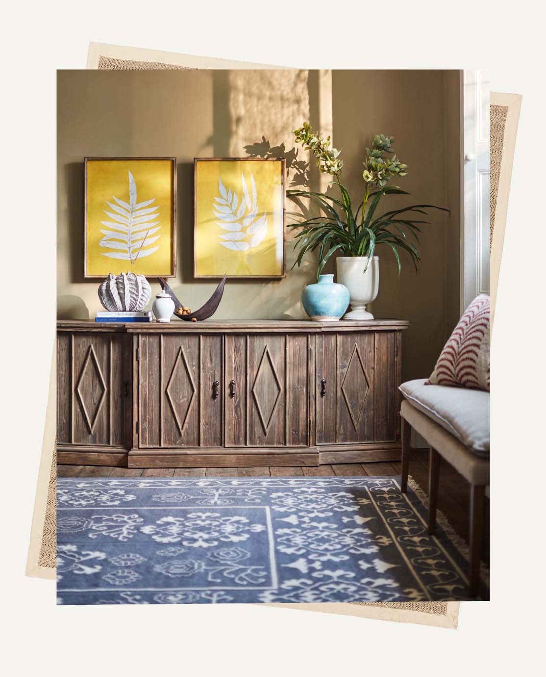 A large navy rug with a white floral print sits on a wooden floor.  A wooden sideboard is in the background.